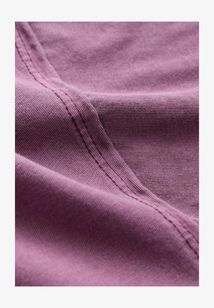 Audinių audinys su nuslopinta purpurine spalva, turintis minkštą, tekstūruotą paviršių su matomomis siūlėmis palei kraštus, sukuriantis sklandžią, plaukiojančią išvaizdą.