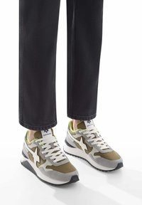 Sneakers con una toma in suede grigio e verde oliva e una parte superiore in mesh, lacci bianchi e suola in gomma nera. Presentano un logo distintivo bianco sul lato.