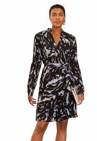 Juoda suknelė su raukiniais, puošta mėlynomis ir pilkomis abstrakčiomis rašmenimis, ilgos rankovės, V formos iškirptė ir atitinkamas diržas.