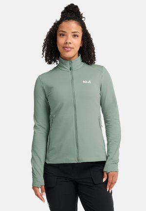 Veste zippée vert clair en matière texturée, avec un col montant, des poches latérales et un logo sur la poitrine.