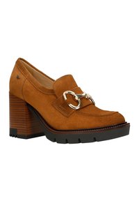 Tan suede heeled shoe with a rounded toe, gold hardware accent, and a chunky wooden heel. Textured sole with a slight platform.