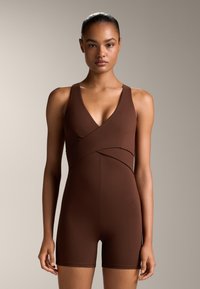 Brun, ärmlös bodysuit med V-ringning och korslagd frontdesign. Tillverkad av slätt, elastiskt tyg, har den en åtsittande form och korta ben.