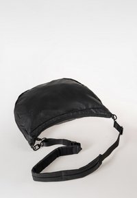 Zwarte nylon crossover tas met een gebogen vorm, verstelbare schouderband en ritssluiting. Glad textuur met minimalistisch ontwerp en geen zichtbare hardware.