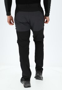 Czarne i szare spodnie outdoorowe o slim fit, z zamykanymi na zamek kieszeniami, wzmocnionymi kolanami oraz gładką, wodoodporną strukturą.