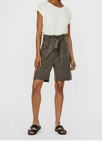 Harmaat bermudashortsit, joissa on solmittava vyö, yhdistetty valkoiseen lyhythihaiseen puseroon ja mustiin sandaaleihin, joissa on hopeiset soljet. Sileä käyttötuntuma.