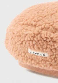 Μαλακό καπέλο από υφή υφάσματος ταμπά αρκουδάκι με μικρή λευκή ετικέτα ραμμένη στη πλευρά.