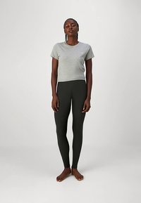 T-shirt gris à manches courtes associé à des leggings noirs, tous deux fabriqués en tissu doux et extensible. Le t-shirt présente un col rond et une coupe ajustée.