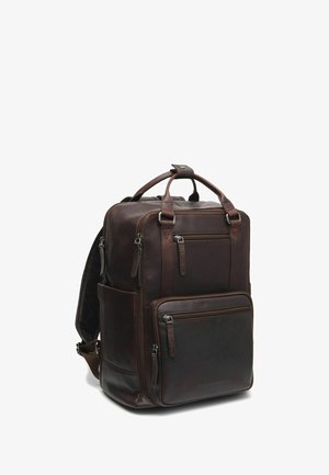 Zaino in pelle marrone con numerose tasche con zip, una maniglia superiore e spallacci imbottiti. Presenta una texture liscia e un design strutturato.