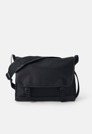 Bolso mensajero negro hecho de tela suave. Cuenta con un cierre de solapa, correa ajustable y dos hebillas en el frente. Forma rectangular compacta.