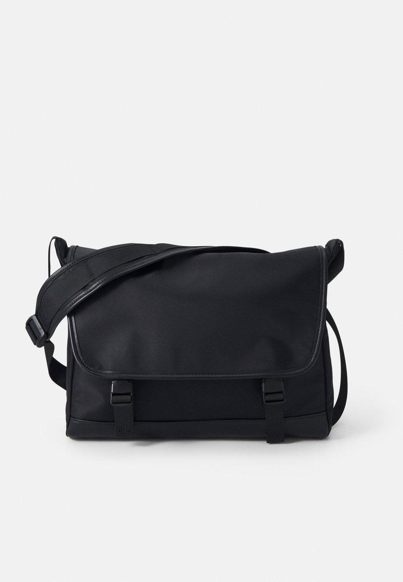 Borsa a tracolla nera realizzata in tessuto liscio. Dispone di una chiusura a patta, di una tracolla regolabile e di due dettagli a fibbia frontali. Forma rettangolare compatta.