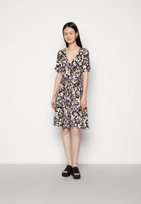 Vestido floral com mangas curtas, decote em V, cintura ajustada e saia fluida, apresentando padrões roxos, amarelos e brancos sobre um fundo escuro.