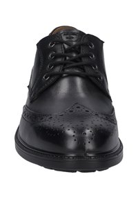 Zwarte leren veterschoenen met een brogue-ontwerp en perforaties, ronde neus, en een contrasterende gestructureerde zool. Glad bovenwerk.