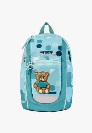 Ein hellblauer Rucksack mit geometrischen Mustern, ausgestattet mit einer Fronttasche mit einem Teddybär-Applikation und einem Reißverschluss. Weiche Stofftextur.