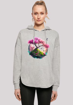 Grauer Kapuzenpullover mit einem großen, bunten Baum-Motiv, das rosa Blüten und grünes Gras in einer kreisförmigen Komposition zeigt. Der Stoff erscheint weich.