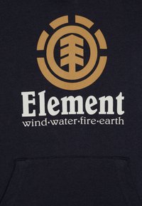 Felpa navy con un grande logo circolare dorato che presenta un design ad albero e la parola "Element." Il testo sottostante recita "vento·acqua·fuoco·terra."