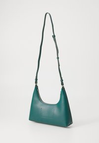 Bolso de mano en color azul verdoso con forma curvada, correa ajustable y cierre de cremallera, exhibido sobre un fondo neutro.