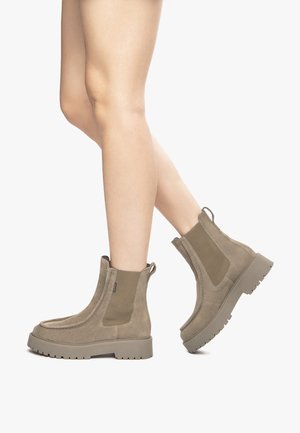 Brown suede ankle boots with elastic side panels, textured surface, chunky rubber soles, and pull tabs on the back for easy wear.