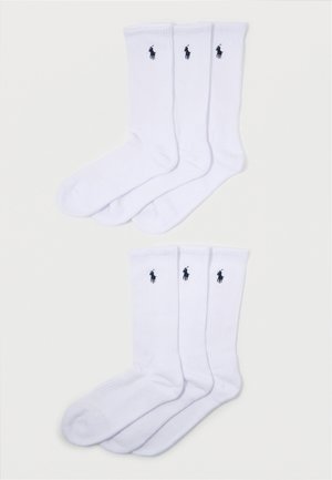 White crew socks with ribbed texture; features a small black polo logo on each sock. Pack contains four pairs with consistent design.