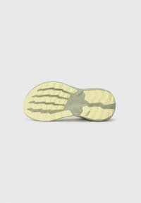 Sneaker sole with light yellow and gray rubber treads featuring geometric patterns and a small rectangular logo near the heel.