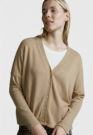 Beige cardigan with a V-neck, button closure, and dropped shoulders. Made from a textured knit fabric. Pairing with leopard print bottom.