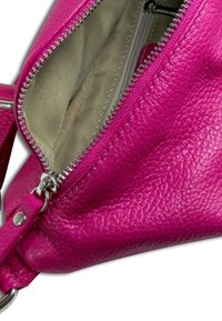 Roze leren tas met een gestructureerd oppervlak, voorzien van een zilveren rits en een beige voering, inclusief een afneembare riem.