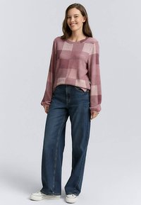 Strikket pullovertrøje i mauve med ternet mønster, kombineret med vidtbenede mørk denim jeans og hvide sneakers.