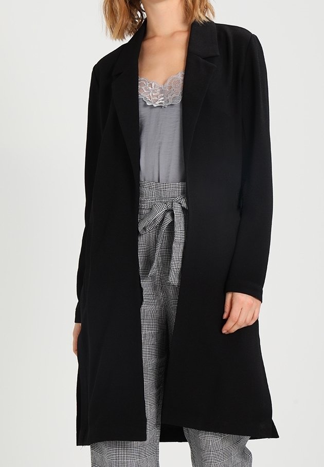Svart långline-kappa med öppen frontdesign, rak skärning och minimalistisk stil. Har ett mjukt tyg, kombinerat med en grå spetsblus och mönstrade byxor.