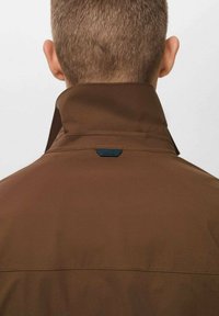 Brown jacket with a high collar, made of a smooth material. Features a small blue tag at the back and a clean, minimalist design.
