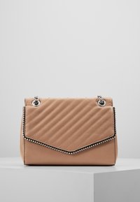 Vaaleanruskea tikkipintainen käsilaukku, jossa on vinonauhatikkaus, hopeiset ketjuhihnat ja hopeanvärinen helminauha läpän reunassa, lepää valkoisella pinnalla.