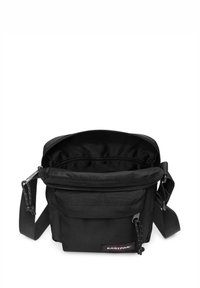 Schwarze Schultertasche mit Reißverschluss oben, aus strapazierfähigem Stoff. Verfügt über einen verstellbaren Riemen, eine Vorderseite mit Tasche und ein Eastpak-Logo-Patch.