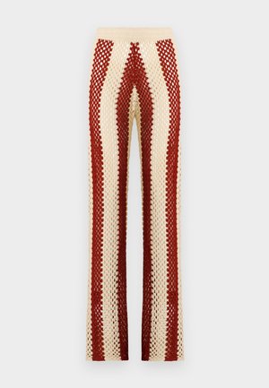 Pantalons au crochet avec une taille ajustée, présentant des rayures verticales alternées rouge et crème, une coupe évasée et une texture ouverte.