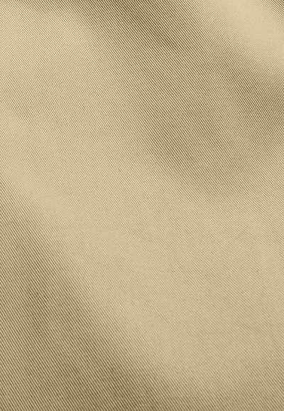 Κοντινό πλάνο απαλού μπεζ υφάσματος με λεπτή διαγώνια ραβδωτή υφή και διακριτική σκίαση.