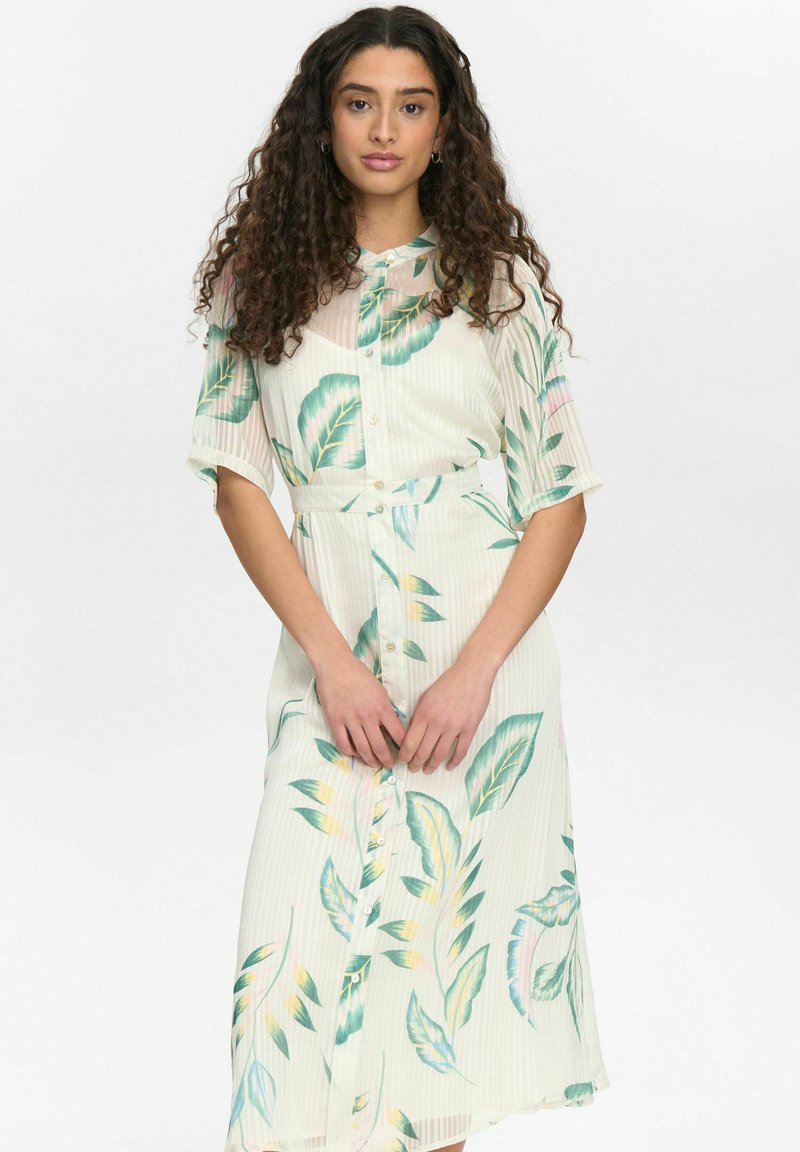 Floral midi haljina svijetlog kremaste boje s uzorkom zelenih listova, kratkim rukavima i dugmadi sprijeda. Teksturirani materijal s pojasom u struku.