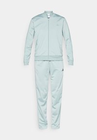 Jasnoniebieski dres z bomberką i zwężanymi spodniami. Wykonany z gładkiej tkaniny, wyposażony w zamek błyskawiczny i haftowane logo na piersi.