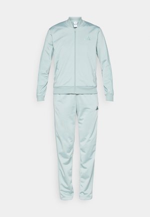 Svijetloplavi trenirka s bomber jaknom i suženim hlačama. Izrađena od glatkog materijala, ima patentni zatvarač i izvezeni logo na prsima.