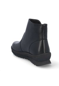 Botín de cuero negro hasta el tobillo con textura suave, puntera redondeada y suela de goma baja. Presenta costuras mínimas y una silueta elegante.