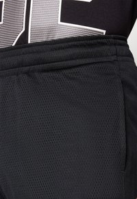 Pantalones cortos deportivos negros hechos de tela de malla ligera y transpirable. Cuentan con una cinturilla elástica y costuras planas para mayor comodidad.