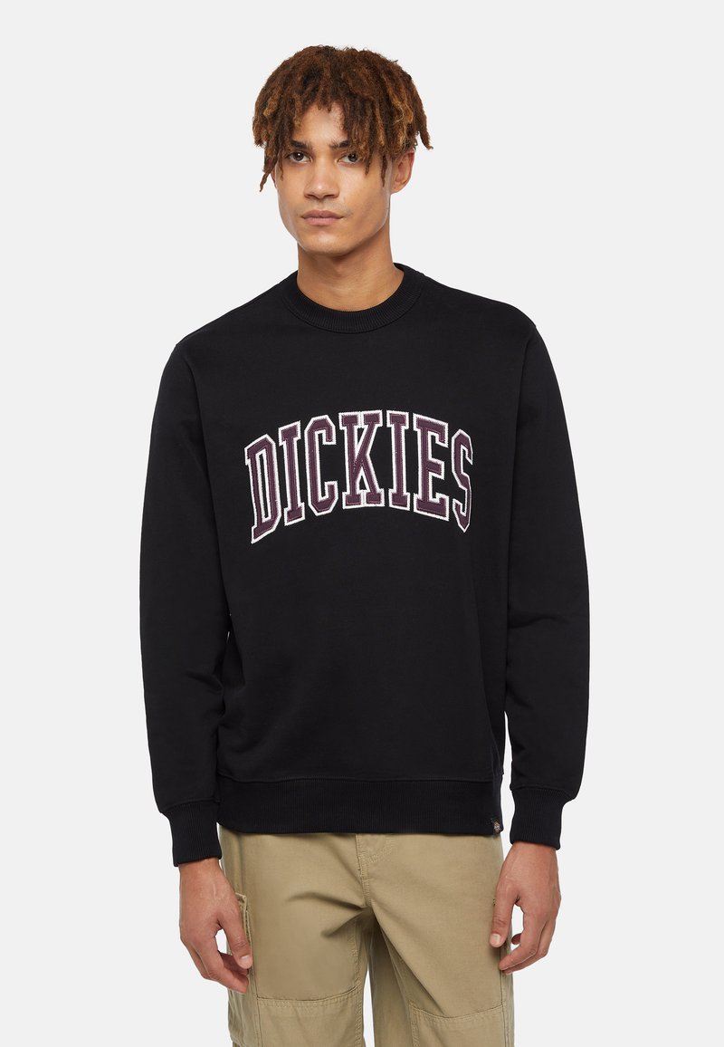 Felpa nera in cotone con polsini e scollatura a costine. Presenta il logo "DICKIES" in lettere bianche e bordeaux sul petto.