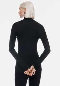 Maglia nera a maniche lunghe con collo alto in tessuto a coste, silhouette aderente, con aperture per il pollice nei polsini delle maniche, design minimalista.