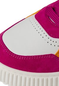 Baskets en daim rose et cuir blanc avec des accents oranges, dotées de détails perforés et d'une semelle en caoutchouc texturé.