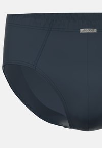 Marinblå simtrosor tillverkade av ett slätt material, med en sydd midjeband och en präglad varumärkeslabel på framsidan.