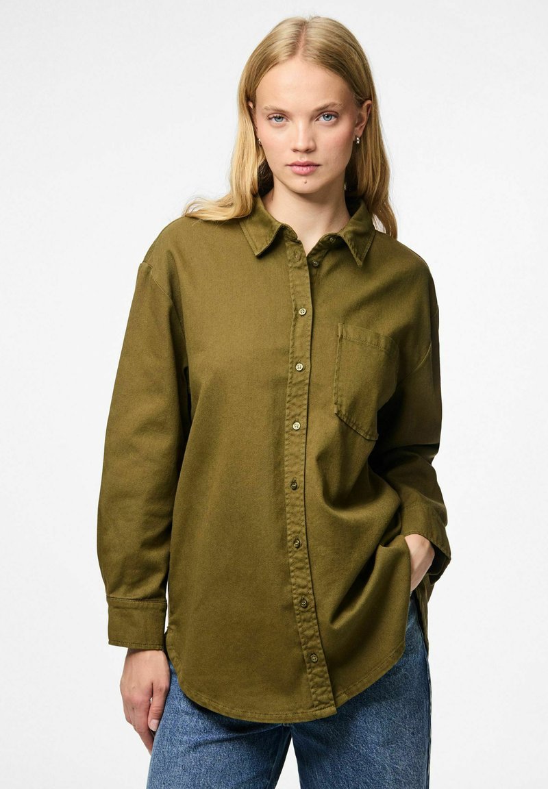 Olivgrön knappad skjorta med spetsig krage, en bröstficka och avslappnad passform. Tillverkad av ett mjukt, strukturerat tyg.