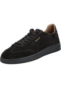 Black suede low-top sneaker with textured sole, black laces, tan inner lining, and gold "GANT" logo on the side.