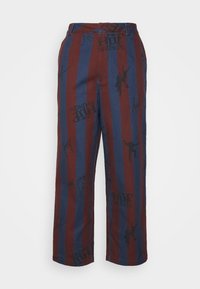 Calças às riscas vermelhas e azuis com um tecido suave, corte descontraído e estampados, incluindo gráficos e texto no material.