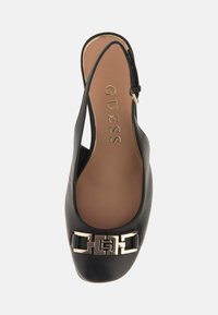Scarpa slingback in pelle nera con punta rotonda, dotata di un dettaglio metallico con logo e una superficie liscia e lucida.