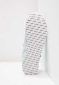 Semelle de basket en bleu clair avec une semelle extérieure blanche texturée et striée. La partie supérieure présente une combinaison de cuir et de matériaux en mesh.