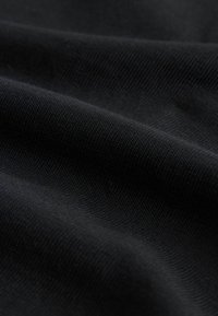 Tela negra con una textura suave, que presenta sutiles patrones tejidos y pliegues suaves que crean profundidad y contraste en el material.