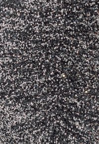 Zwart paillettenstof met een gestructureerd oppervlak. Voorzien van reflecterende ronde pailletten, gerangschikt in een zigzagpatroon, die glans en diepte toevoegen.