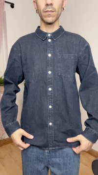 Mørk denim skjorte med buet krage, lange ermer og brystlomme. Har metallknapper og en myk tekstur.