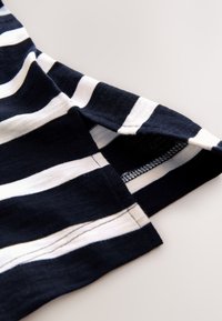 Navy and white striped cotton t-shirt showing a side slit with a clean hem and short sleeves, highlighting its soft texture and flexible design.